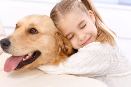Golden Retriever puppy being hugged by little girl
