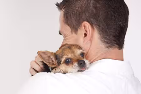 Man cuddling puppy on his shoulder